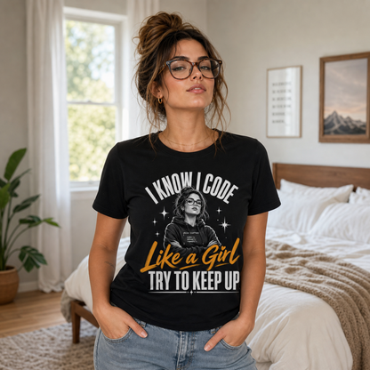 A woman wearing a black graphic t-shirt with the text 'I KNOW I CODE Like a Girl TRY TO KEEP UP' and a graphic of a woman with glasses, standing in a bright bedroom.